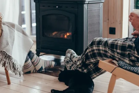 Zwei Personen mit Katze vor Kaminofen